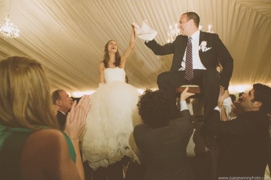 Joyful bride and groom lifted on chairs at wedding party