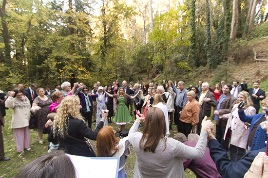 Large group holding hands in a forest ceremony