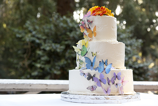 Three-tiered wedding cake decorated with colorful butterflies
