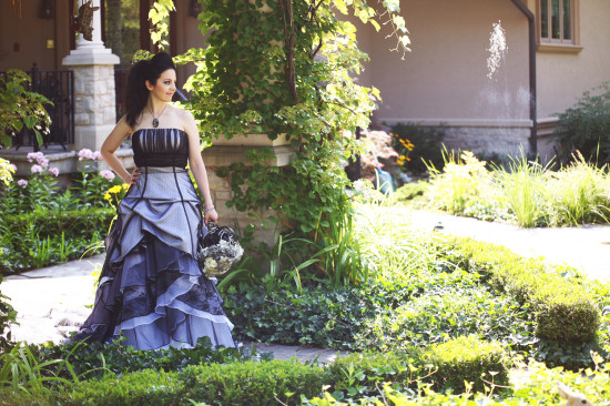 Elegant bride in gothic wedding dress stands in garden
