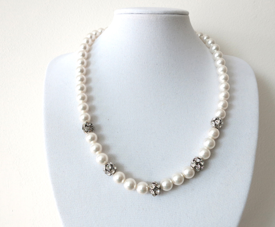 Elegant pearl necklace with crystal accents on a white stand