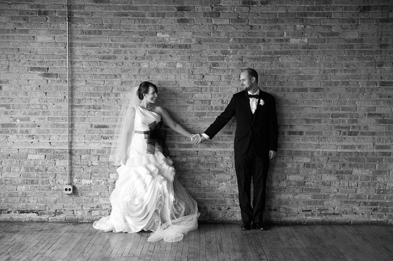 Bride and groom hold hands, smiling, wedding photo, black and white