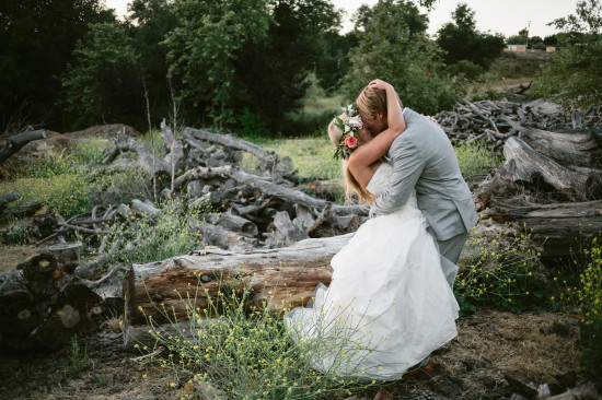 Newlyweds share a romantic kiss in a rustic outdoor wedding