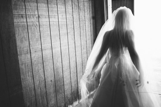 Bride in dress and veil backlit by bright light