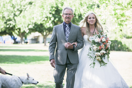 Bride walking down the aisle with her father on a sunny wedding day