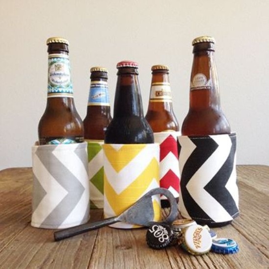 Beer bottles in patterned koozies with opener and caps on wood