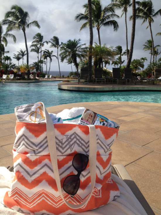 Beach bag with sunglasses by the pool and palm trees background