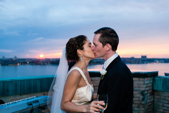 Wedding couple kissing at sunset with water in the background