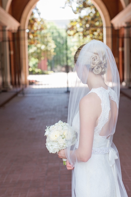Bride in white dress holding bouquet, looking down at wedding