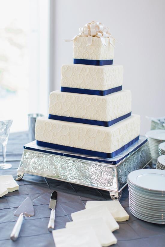 Elegant four-tiered wedding cake with blue ribbon, ready to be served
