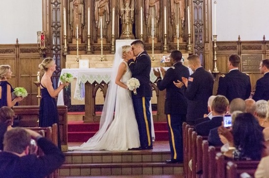Bride and groom share a kiss at the alter of their wedding ceremony