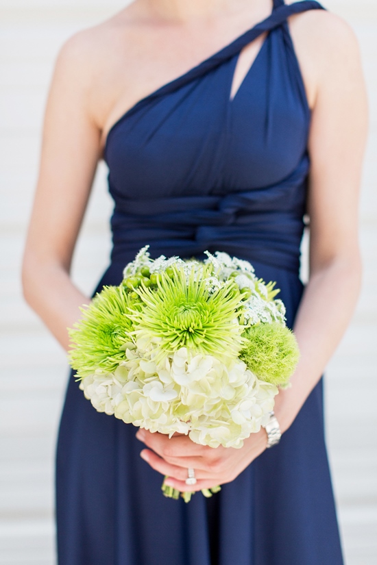 Woman in navy dress holding green and white flower bouquet