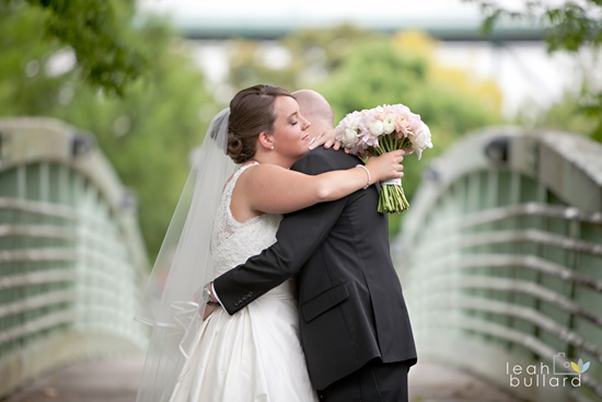 Bride and groom embrace, holding bouquet, wedding day love