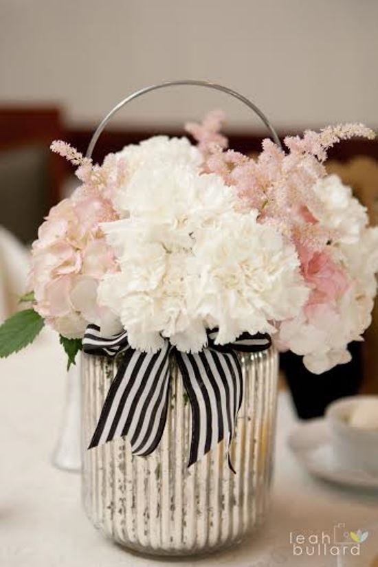 Elegant floral arrangement in a silver vase with a striped bow