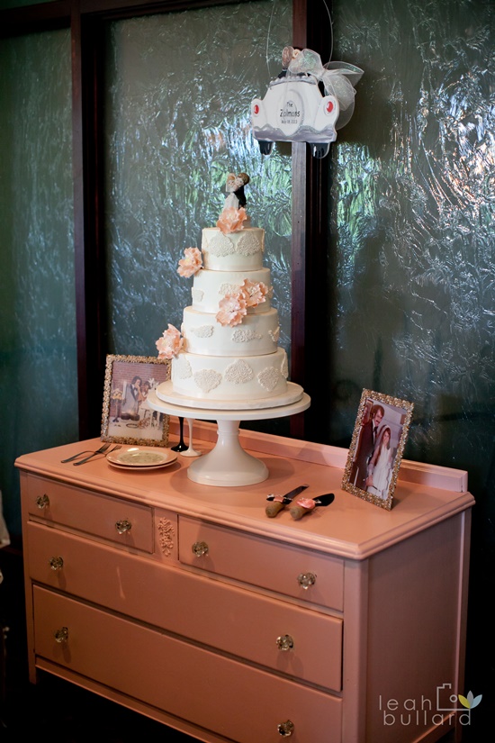 Elegant wedding cake on pink dresser with decorations and photos