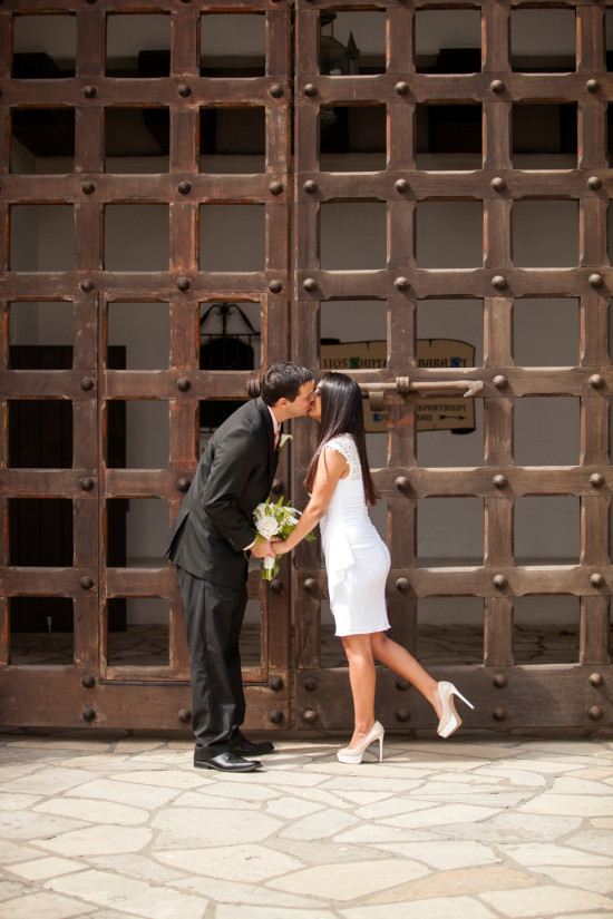 Newlyweds share a kiss in front of large wooden doors