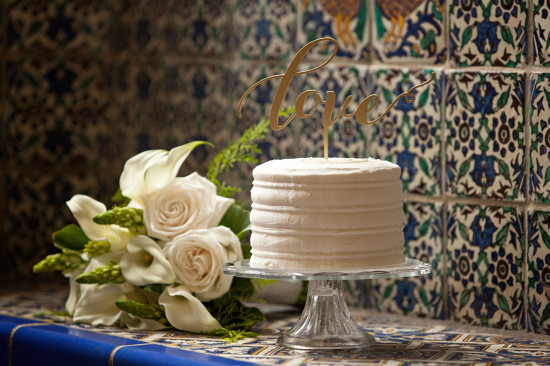 Wedding cake with love topper and white roses in romantic setting