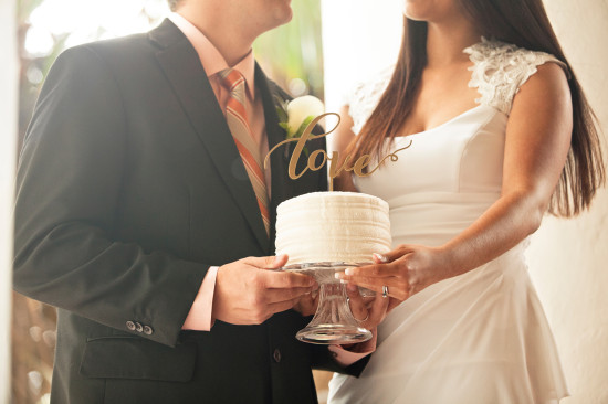 Wedding couple holding a love themed cake on their special day