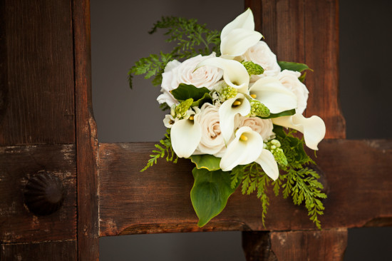 Elegant white calla lily bouquet against weathered wooden cross