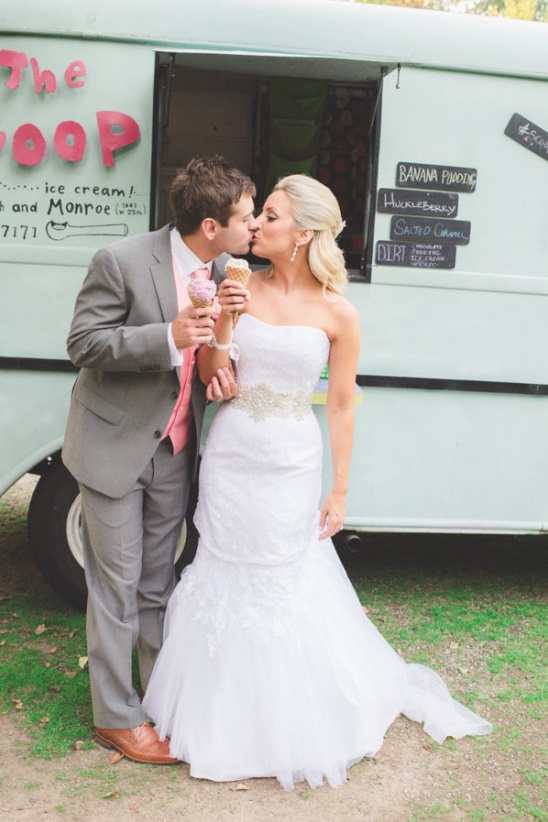 Newlyweds share ice cream and a kiss near an ice cream truck at their wedding