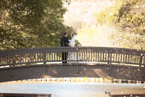 Couple stands on a bridge over water on their wedding day
