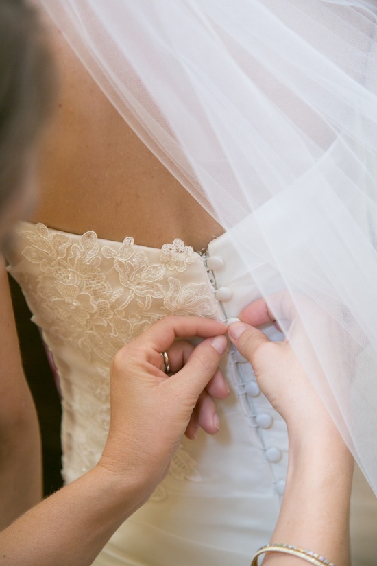 Bridesmaids help buttoning wedding dress details before ceremony