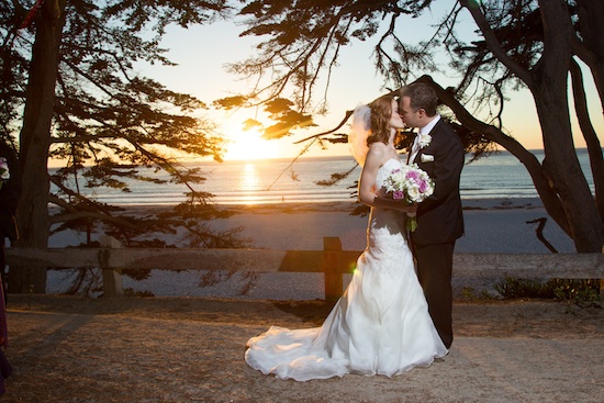 Romantic wedding kiss by the beach at sunset for a couple
