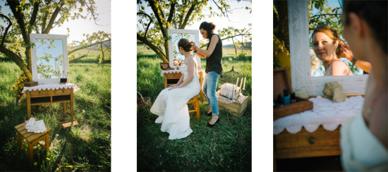Bride gets ready outdoors with hair stylist in a mirror reflection