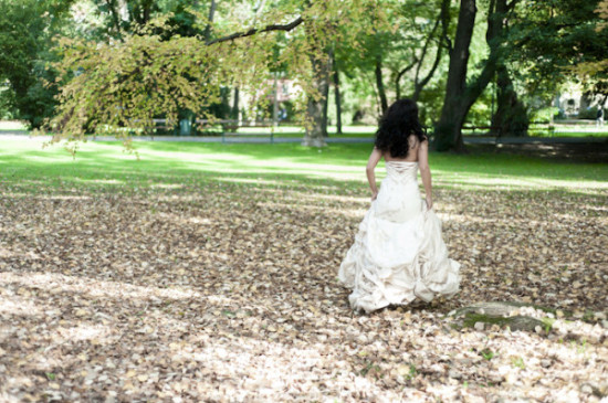 Woman in wedding dress walking through autumn leaves