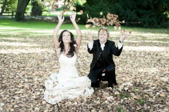 Happy couple throwing leaves on their wedding day in a park