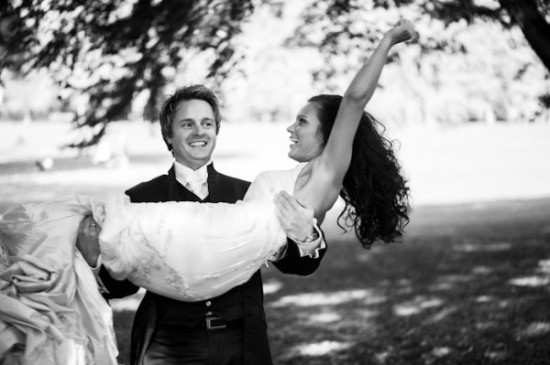 Groom carries bride in arms during wedding celebration