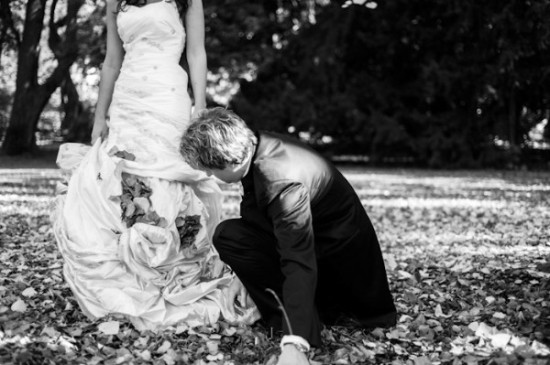 Groom helping bride with her dress during a wedding photo