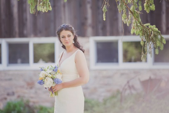 Beautiful bride holding a bouquet in front of a rustic building