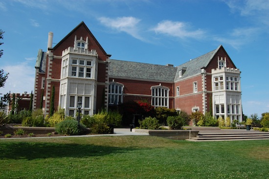 Elegant brick mansion with manicured grounds and blue sky
