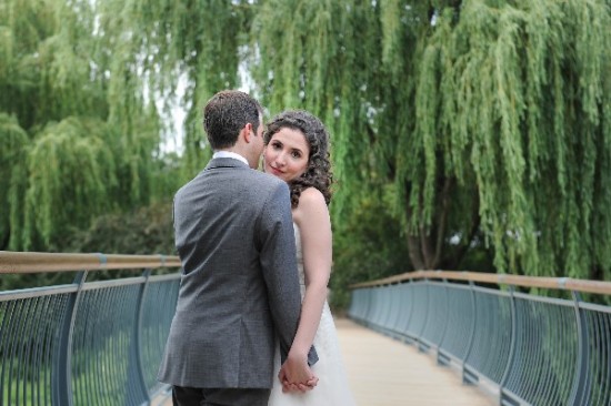 Wedding couple holding hands on a bridge with lush greenery