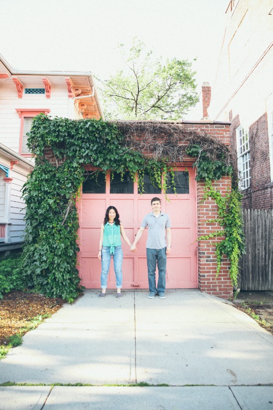 Couple holding hands in front of pink ivy covered garage