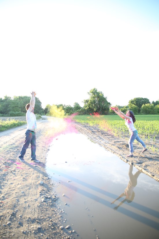 Couple throwing colorful powder over a puddle on a path