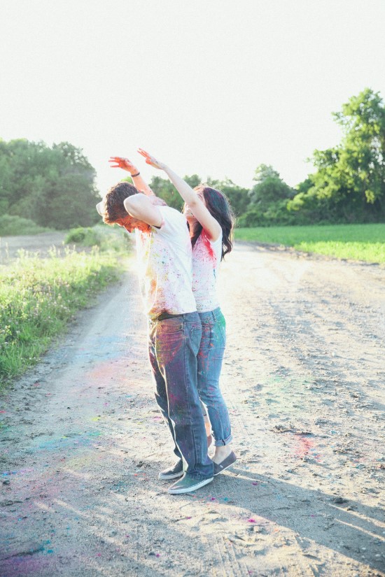 Couple celebrating with colorful powder in a bright field