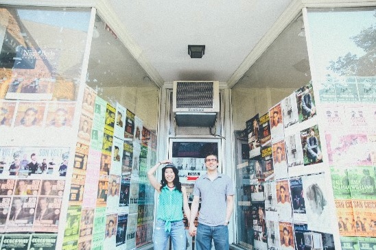Couple poses outside shop covered in music posters