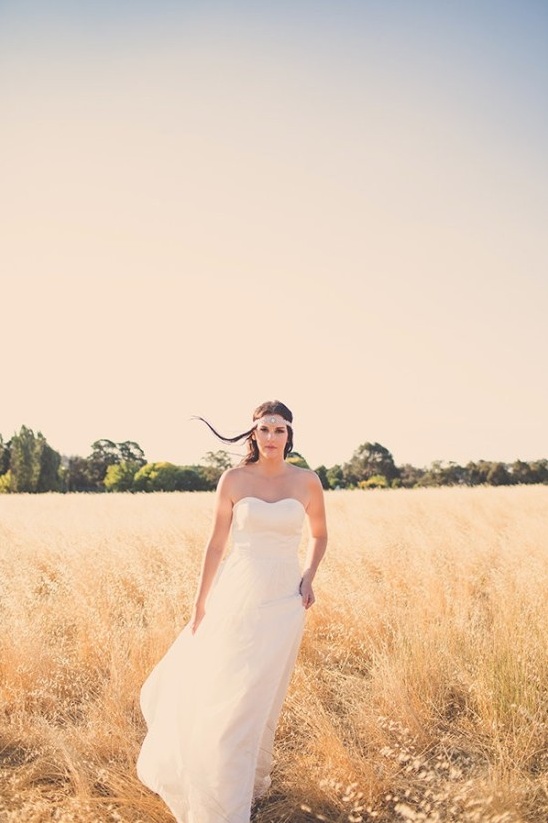 Bride in flowing gown walks through golden wheat field