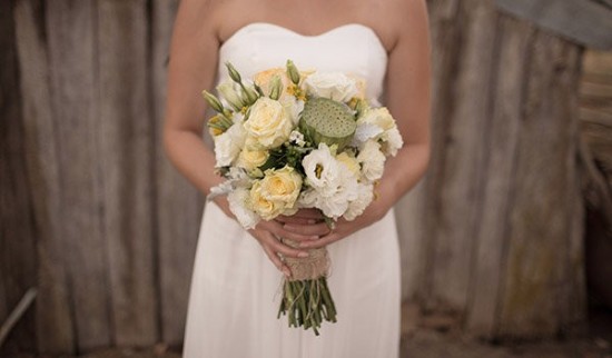 Bride holds yellow and white floral wedding bouquet