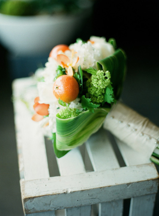A unique wedding bouquet with orange accents and lush greenery