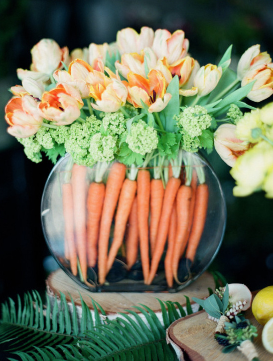 Creative floral arrangement with carrots and orange tulips in a vase