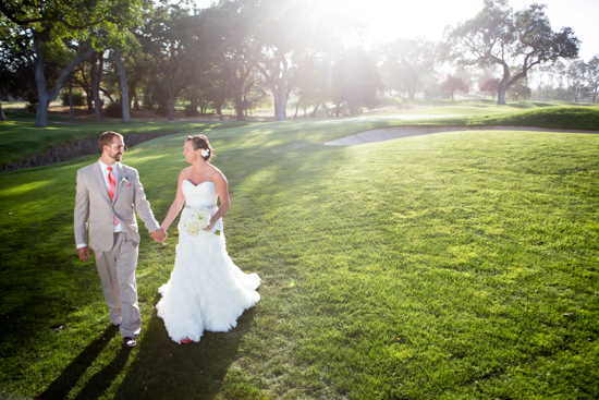 Bride and groom walk on green at outdoor wedding