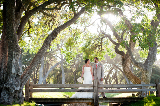 Bride and groom pose on bridge at outdoor wedding venue