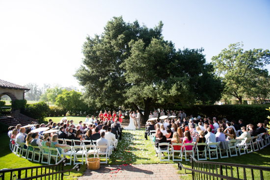 Outdoor wedding ceremony with guests and a large tree