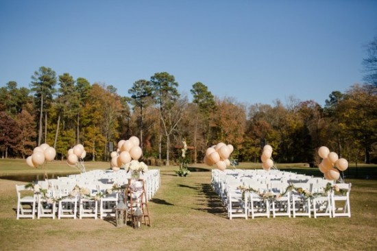 Outdoor wedding ceremony with white chairs and balloons