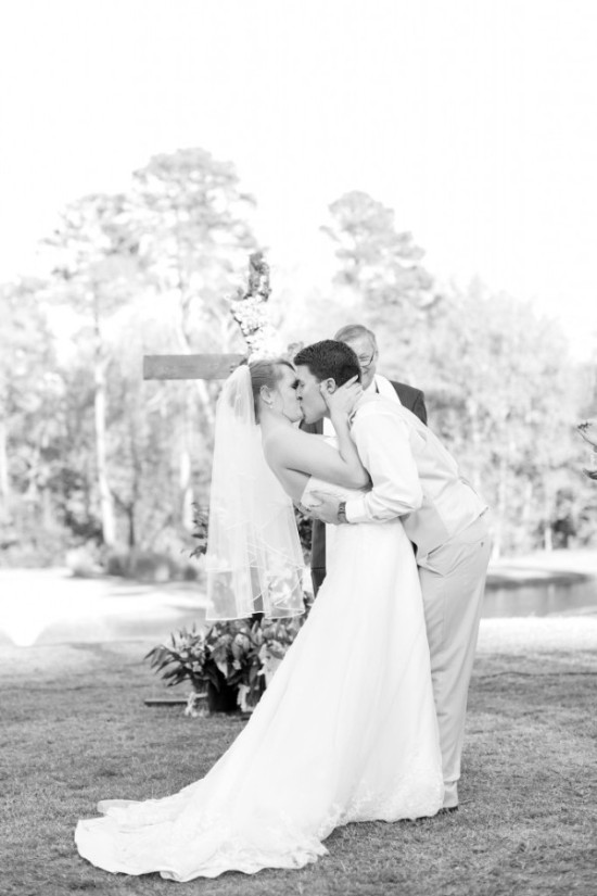 Bride and groom share a kiss at outdoor wedding ceremony