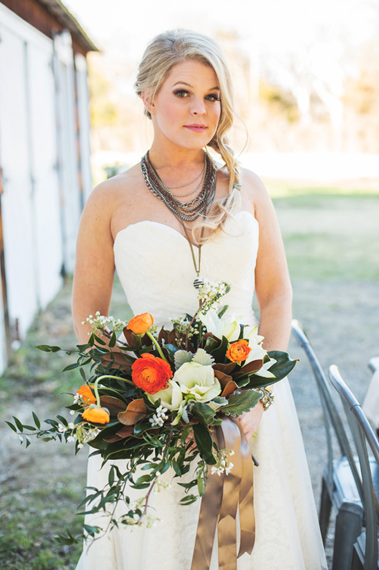 Blonde bride in a white dress holding orange flowers