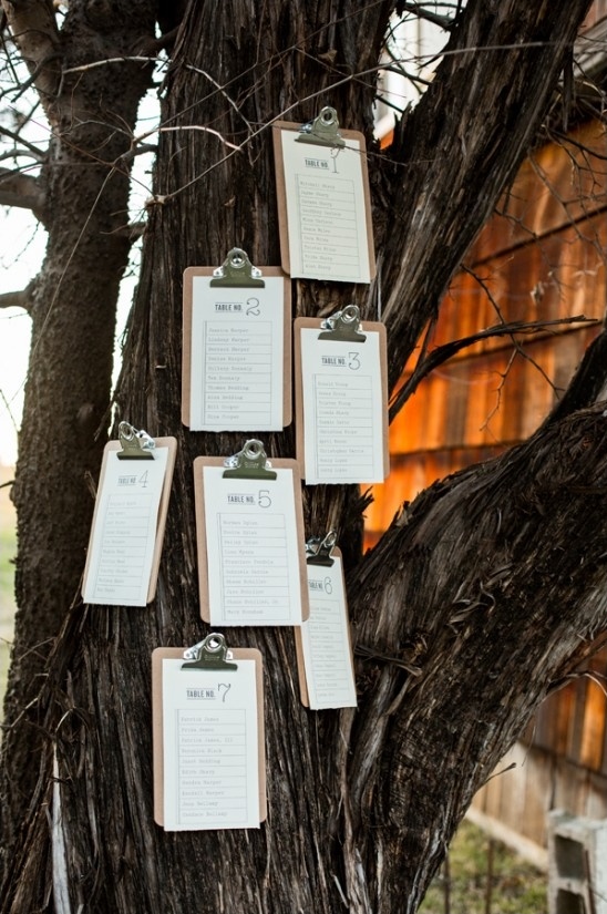 Seating chart clipboards on tree trunk rustic wedding